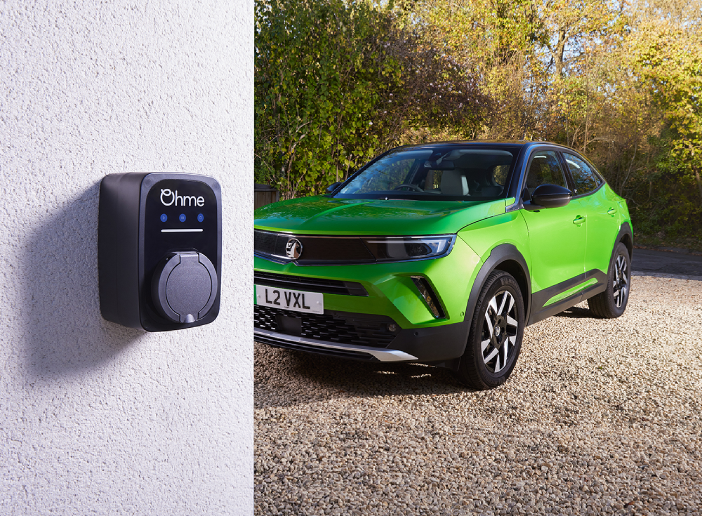 Ohme ePod untethered EV charger mounted on exterior wall beside bright green Vauxhall Mokka electric vehicle